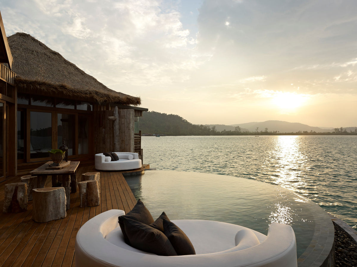 Overwater bungalow with a pool and view of the water during sunset.