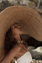 Woman wearing a large straw hat and cream bikini  in a natural setting
