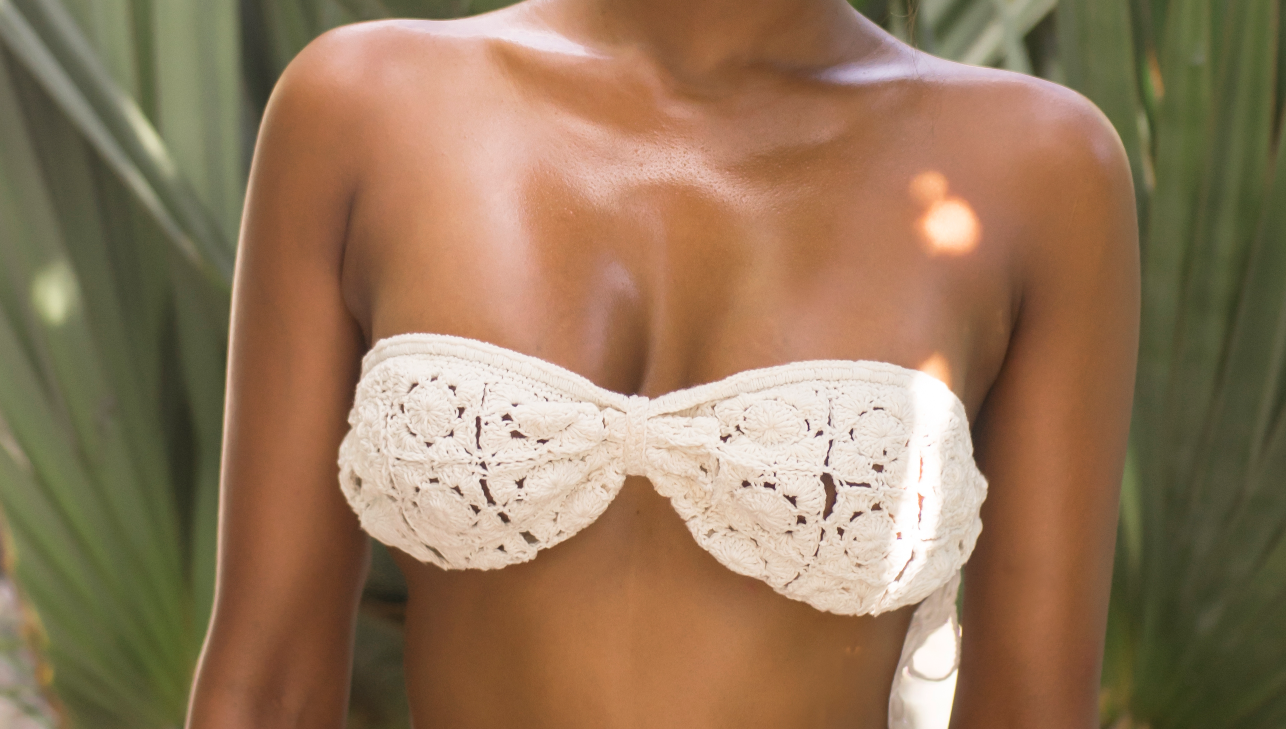 White crochet bikini top worn by a person with a blurred natural background