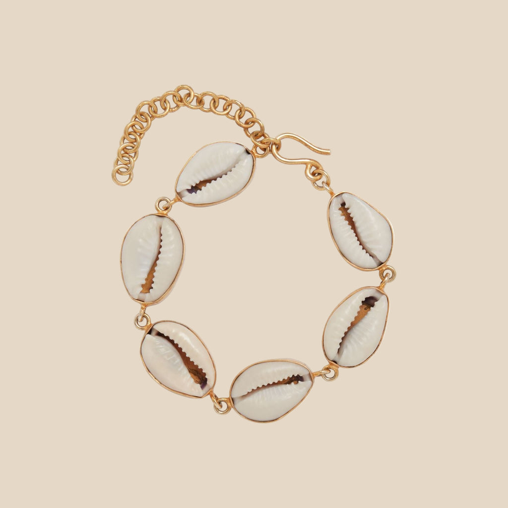 Bracelet with Cowrie Shells on a gold chain against a white background