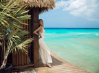 Woman in a white dress standing on a wooden deck by the ocean
