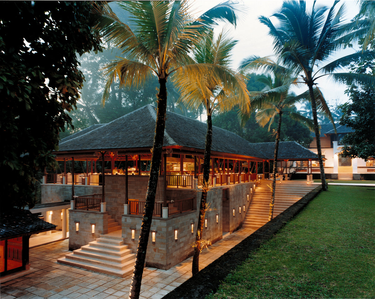 Modern building with a tropical setting featuring palm trees and greenery.
