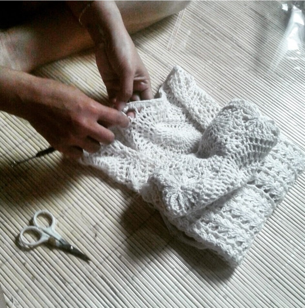 White handmade crochet on a textured surface with a pair of scissors nearby.