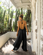 Woman in a black jumpsuit standing on a wooden deck with cacti in the background