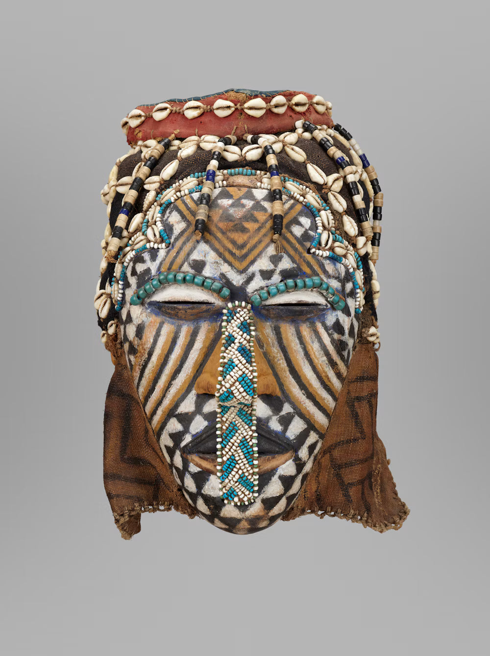 A face mask from the Kuba tribe from Africa with cowrie shell and beading detailover a painted mask face