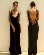 Black evening gown with open back design worn by a model against a plain background