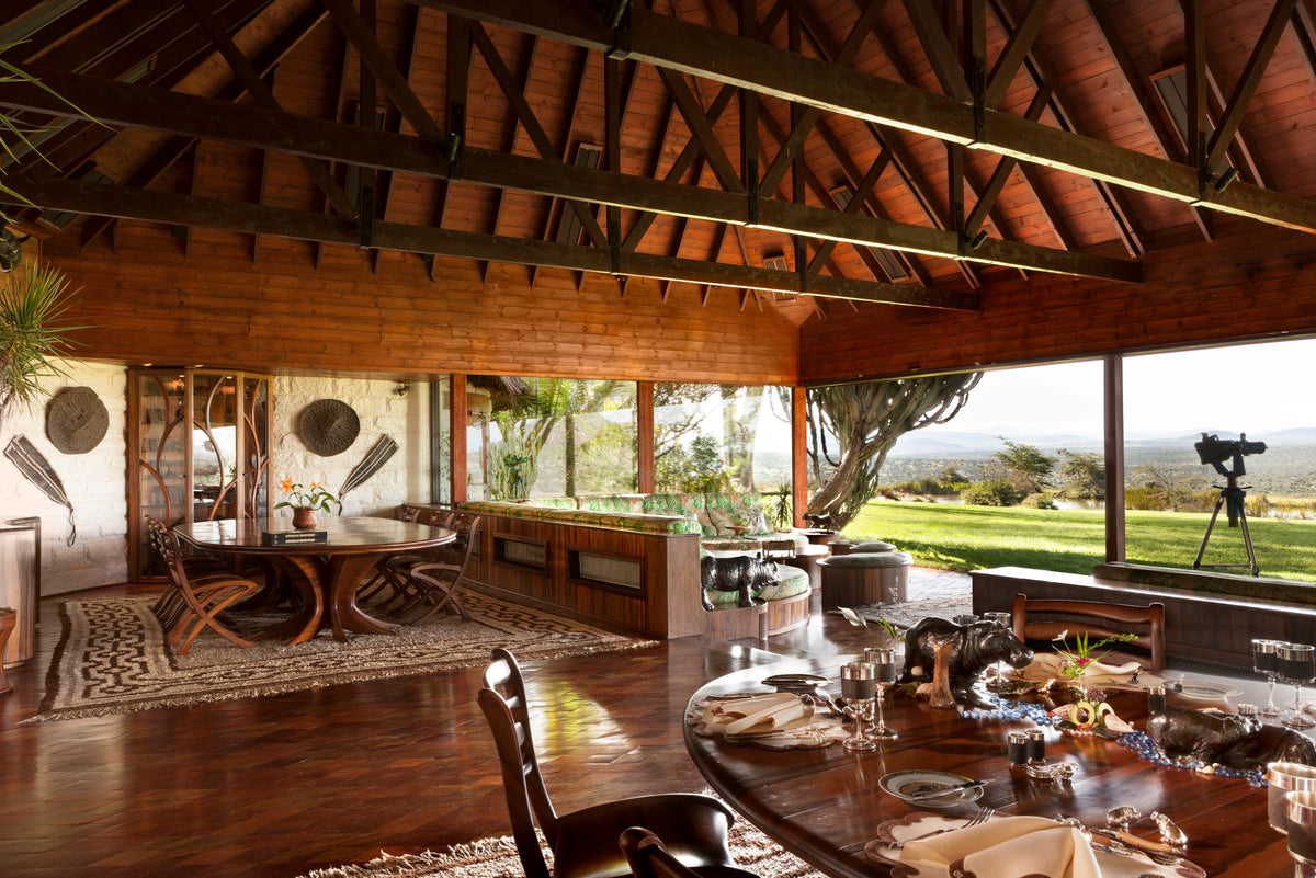 Wooden interior with large windows, outdoor view, and dining table.