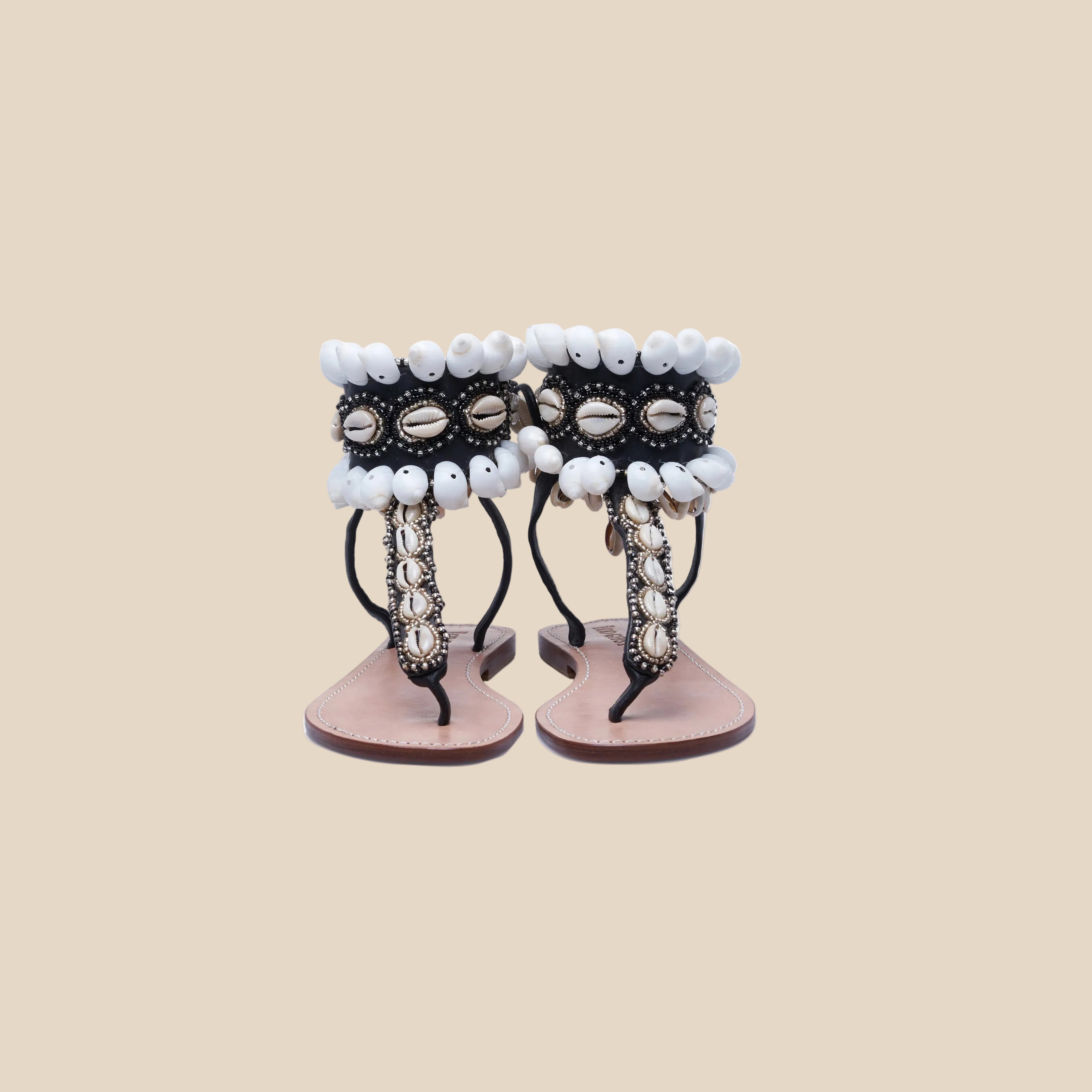 Pair of sandals with decorative shell straps on a white background