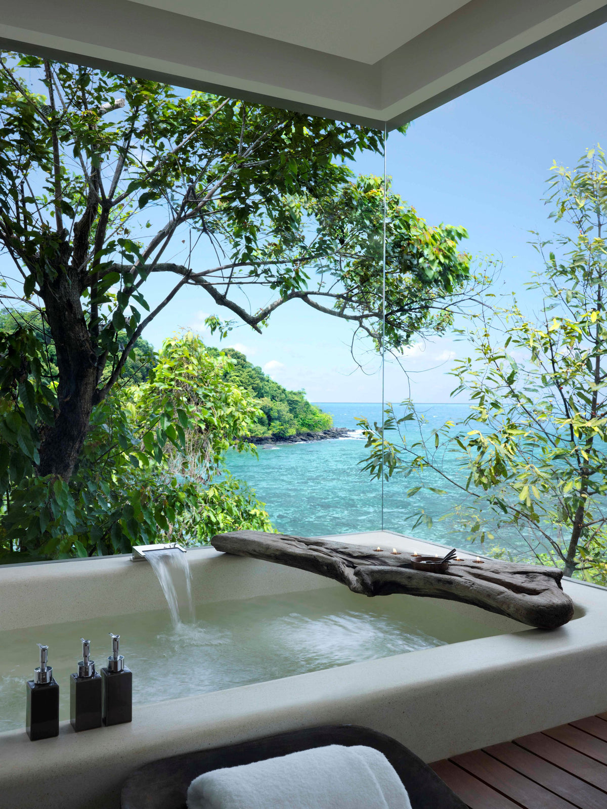 Outdoor bathtub with ocean view and tree branches