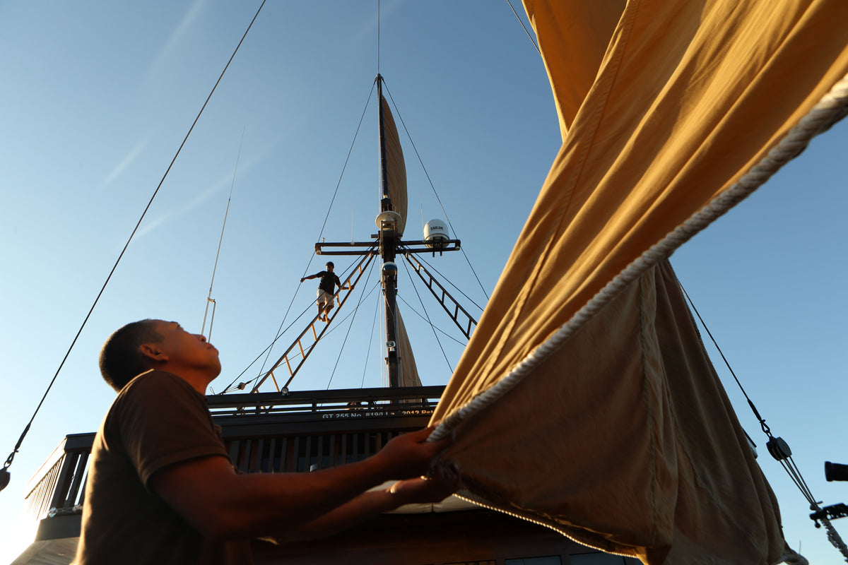 Crew on a ship  checking the sails with a clear blue sky