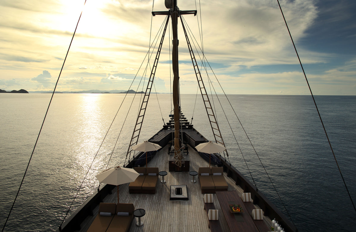 Sailing ship on the ocean with sunset or sunrise