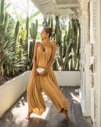Woman in a camel jumpsuit standing on a wooden deck with cacti in the background